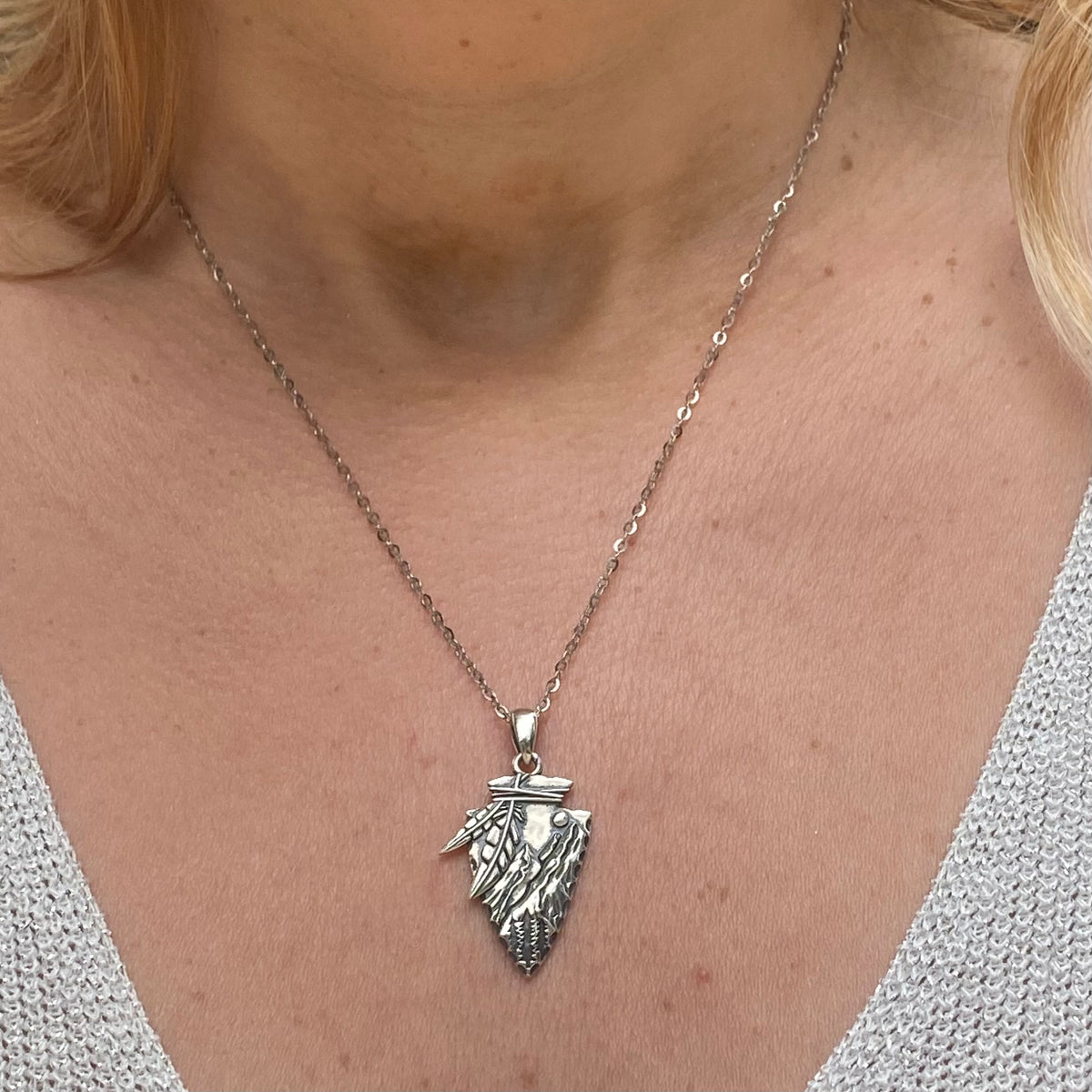 Arrowhead necklace sterling silver with detailed feather design worn on a silver chain