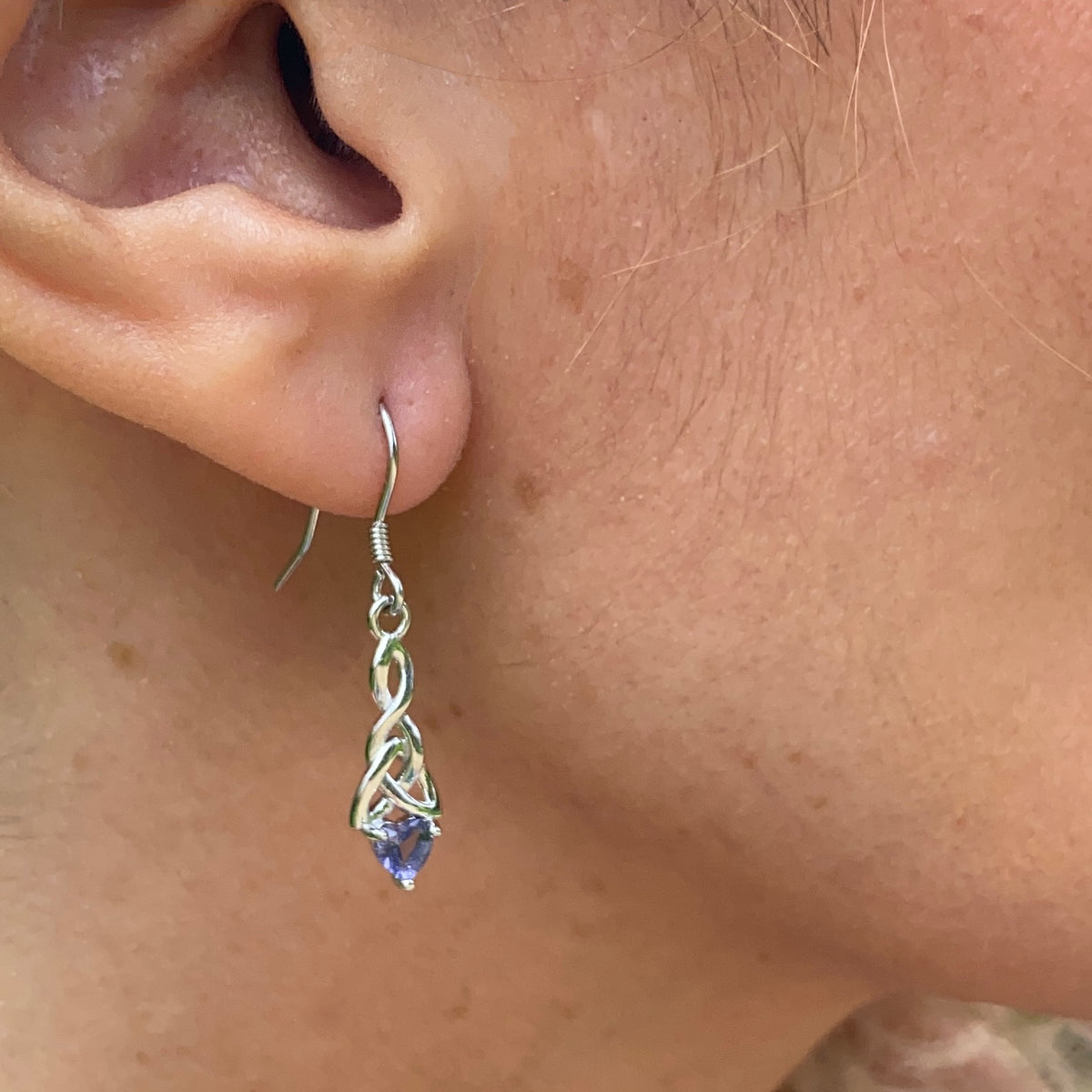 Sterling silver birthstone trinity knot dangling earrings worn on ear showcasing detailed craftsmanship