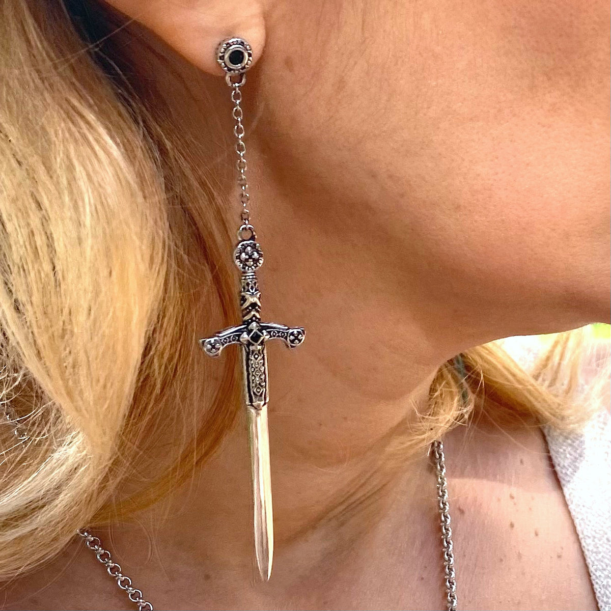 Close-up of woman wearing sterling silver sword earrings with intricate detailing by Miss Valkyrie