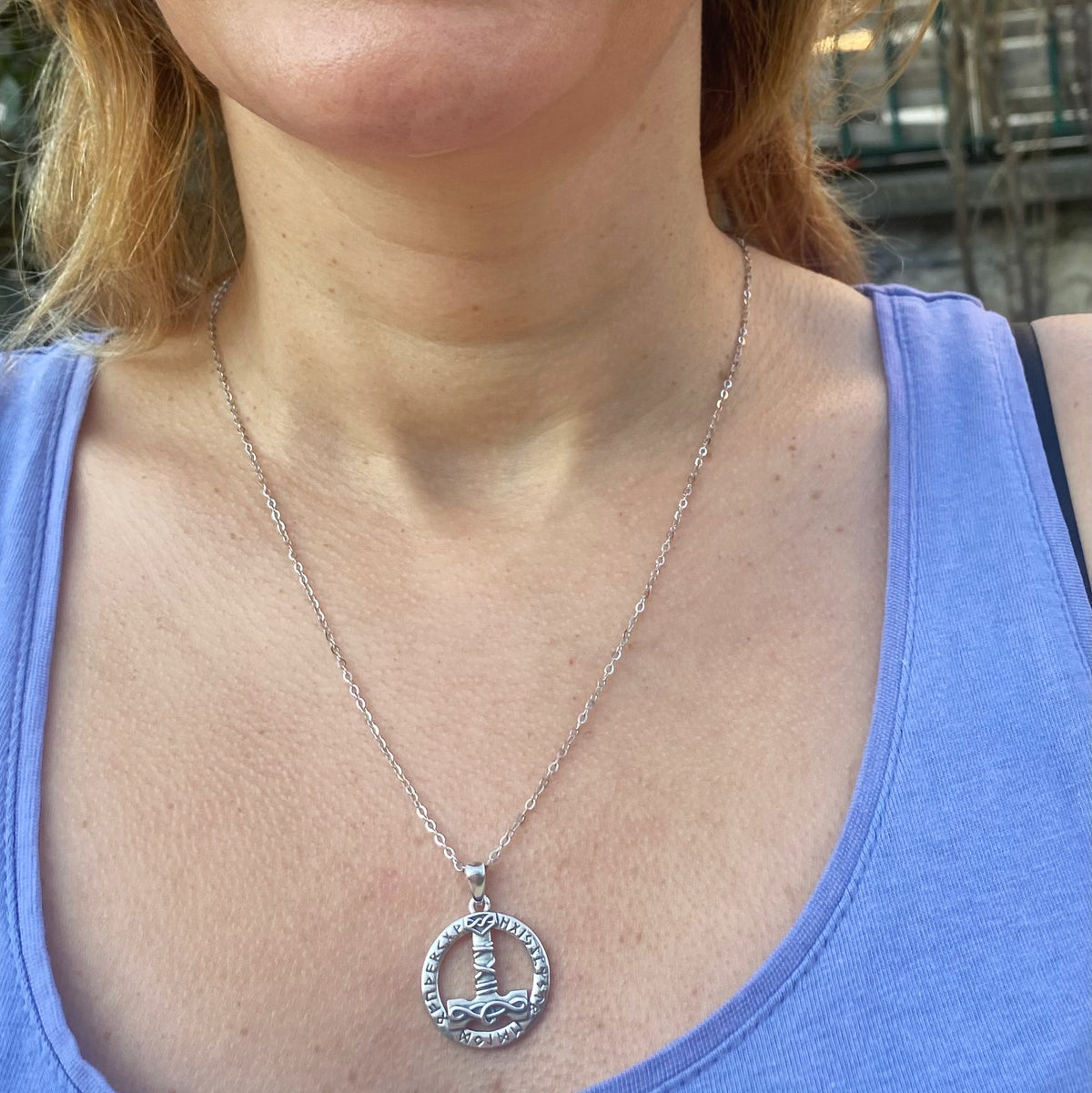Sterling silver Thor's hammer mjolnir necklace worn on a silver chain with circular pendant detail