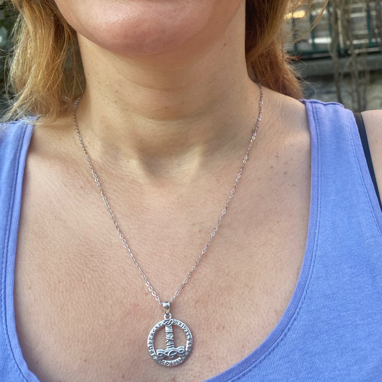 Sterling silver Thor's hammer mjolnir necklace worn on a silver chain with circular pendant detail