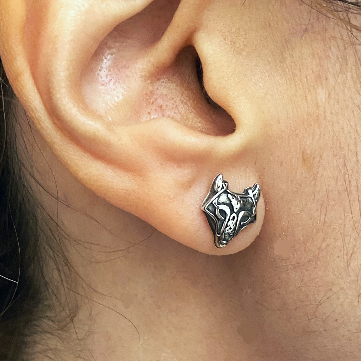 Sterling silver wolf earrings worn on ear showing detailed wolf head design by Miss Valkyrie