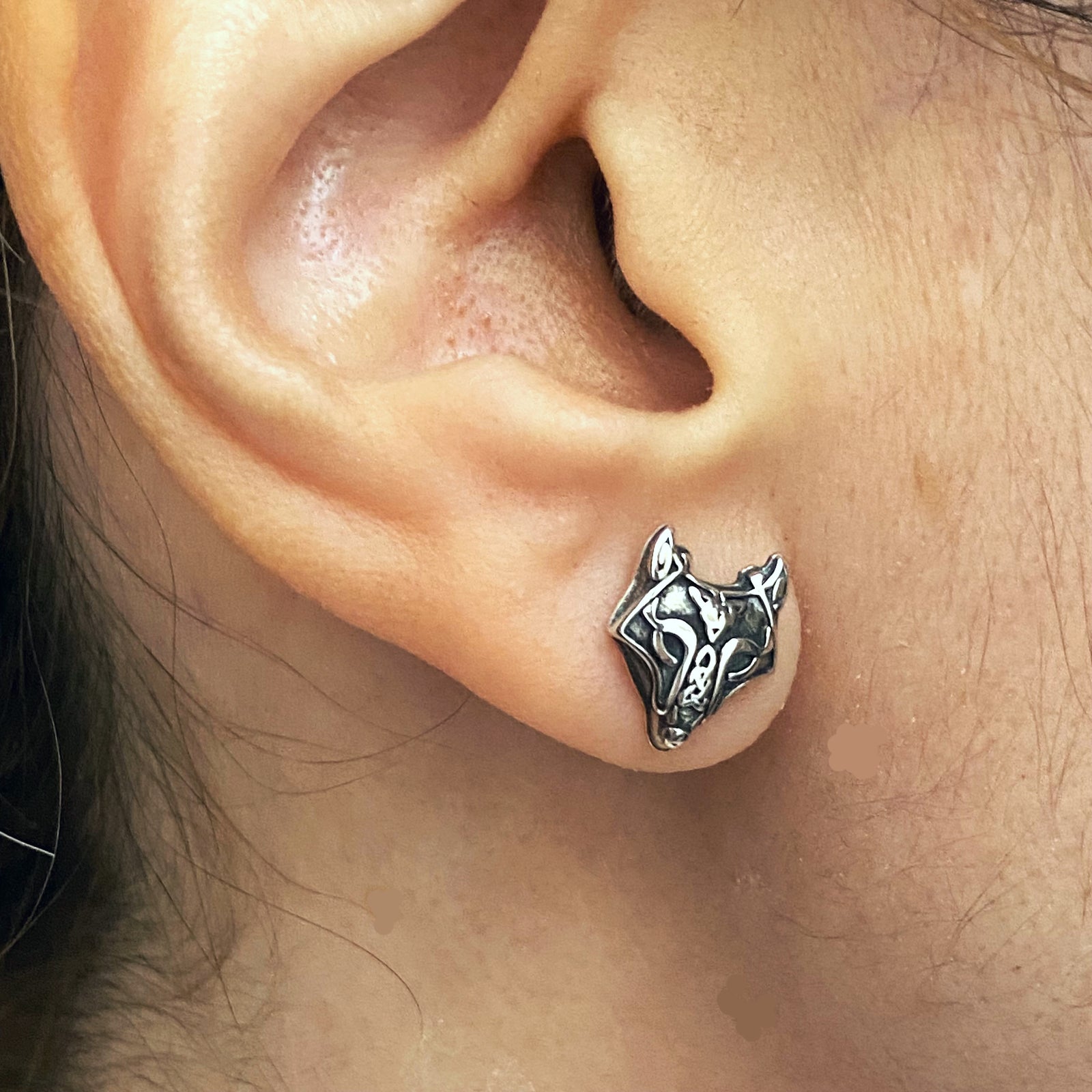 Sterling silver wolf earrings worn on ear showing detailed wolf head design by Miss Valkyrie